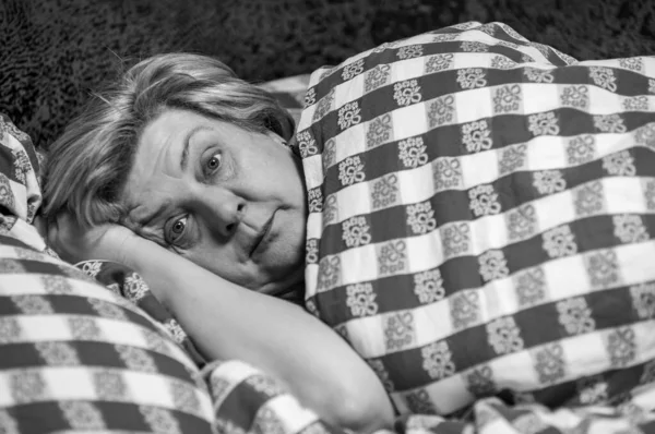 一个成熟而丰满的女人在家里休息的画像 躺在沙发上看着摄影师 免版税图库图片