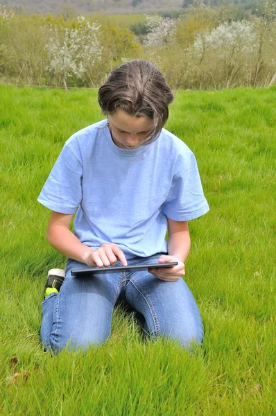 芝生の上に座って、デジタル タブレットを使用しての女の子 — ストック写真