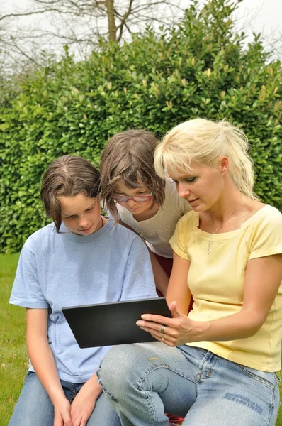 Famiglia seduta sul prato e utilizzando tablet digitale — Foto Stock