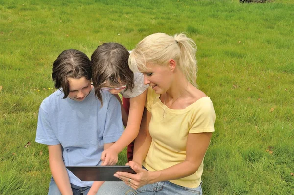 Family sitting on the lawn and using digital tablet — Stock Photo, Image