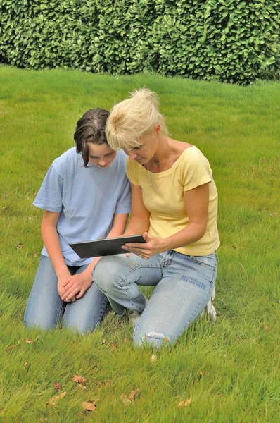 Rodzina siedzący na trawniku i za pomocą cyfrowego tabletu — Zdjęcie stockowe