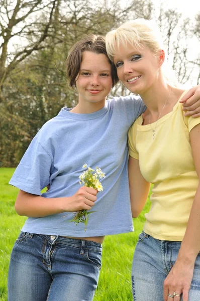 Datter tilbyder blomster til sin mor - Stock-foto