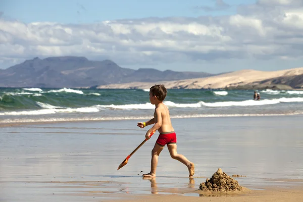 Menino brincando na praia Fotos De Bancos De Imagens