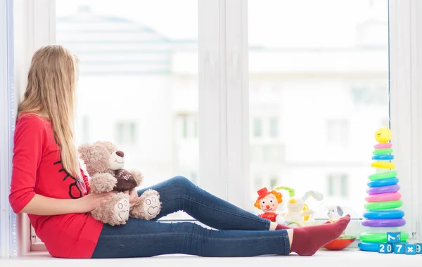 Chica con juguetes en un alféizar de ventana — Foto de Stock