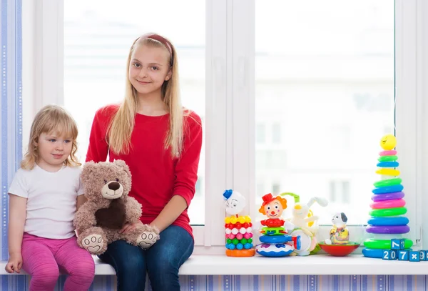 Vriendinnen met een speeltje op de vensterbank zitten. — Stockfoto