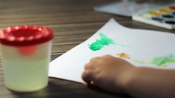 Mano infantil con pinceles dibujo sobre papel blanco — Vídeo de stock