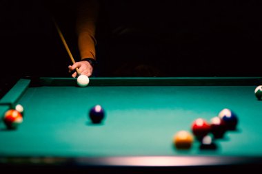 Salondaki bilardo masasında beyaz toplar ve erkek eli.