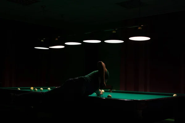 Foto de alto contraste de um jogador em uma mesa de bilhar no escuro. — Fotografia de Stock