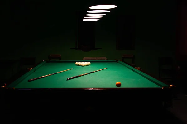 Uma mesa de bilhar, banhada em lamplight contra um fundo escuro. — Fotografia de Stock