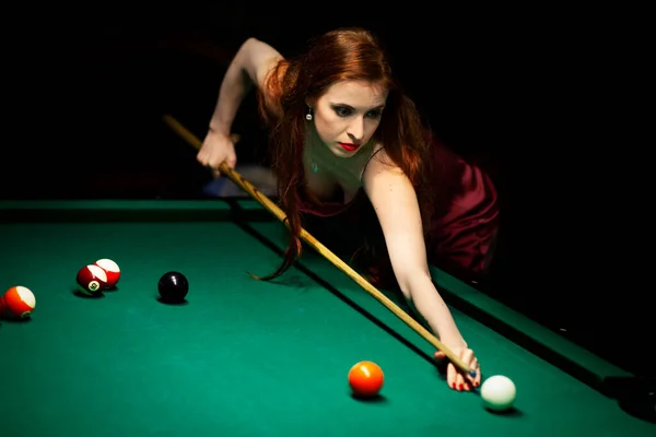 Femme visant la table de billard dans la chambre noire — Photo