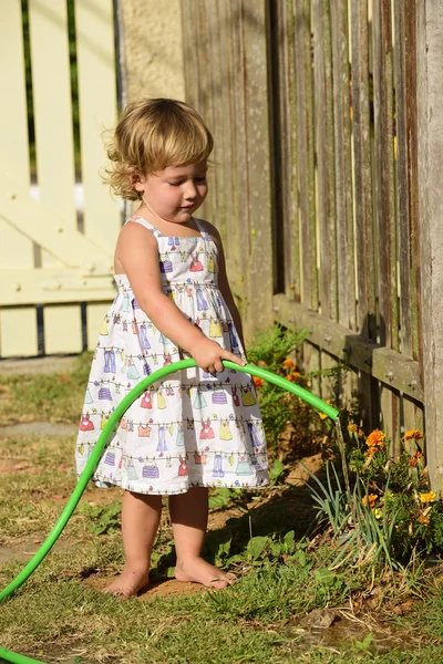 Kid vattna blommor i trädgården — Stockfoto