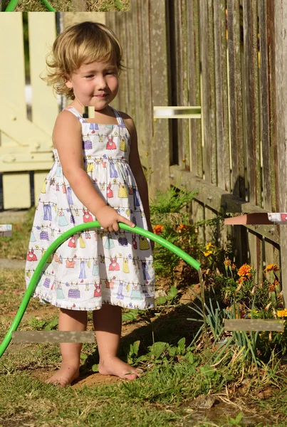 Niño regando flores en el jardín — Foto de Stock