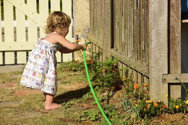 Kid vattna blommor i trädgården — Stockfoto