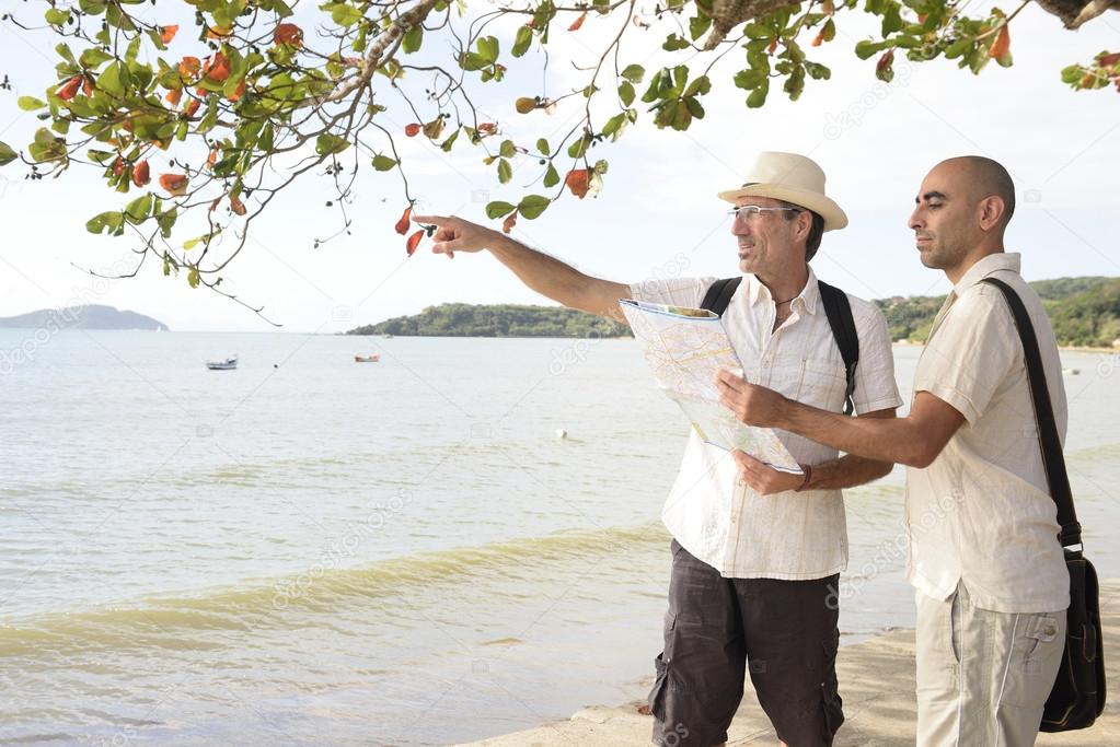 Gay couple on vacation pointing at destination