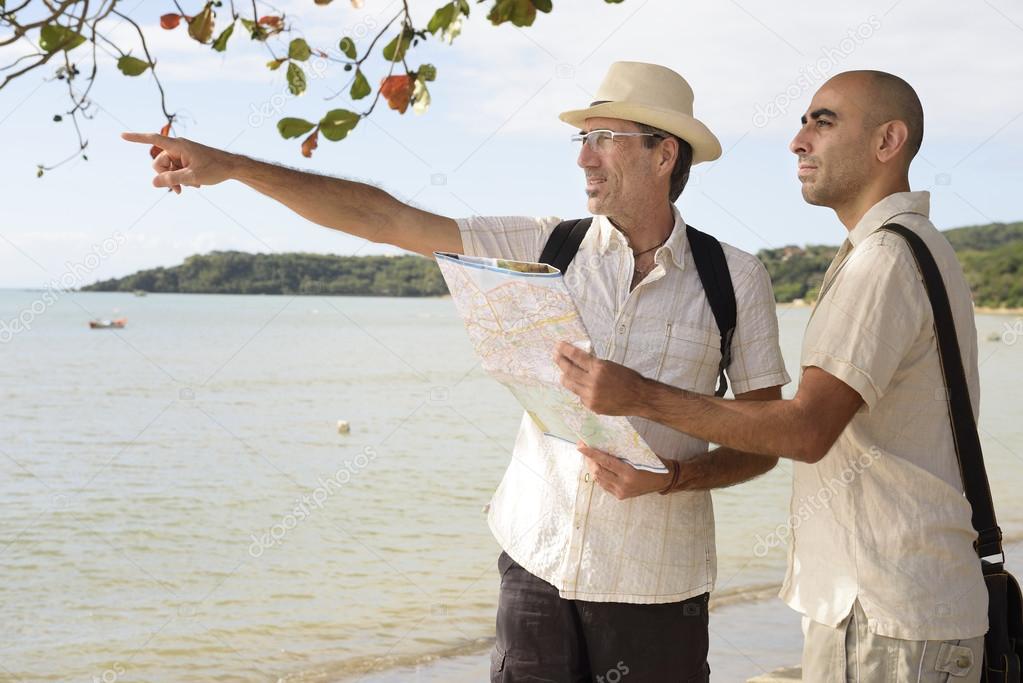 Gay couple on vacation pointing at destination