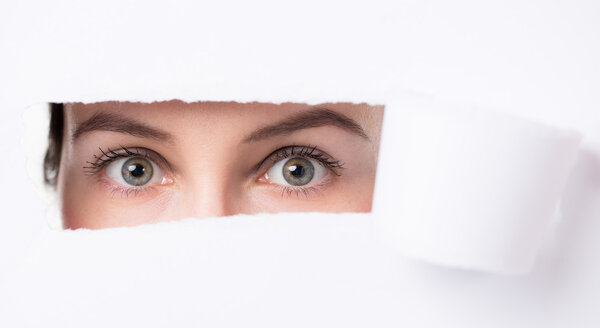 Women  eyes through a hole in a paper