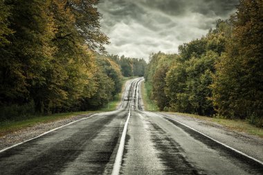 Bir fırtına gökyüzü altında karanlık asfalt yolu