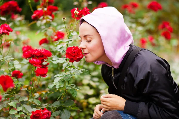 Jovem mulher cheirando rosas em um jardim — Fotografia de Stock