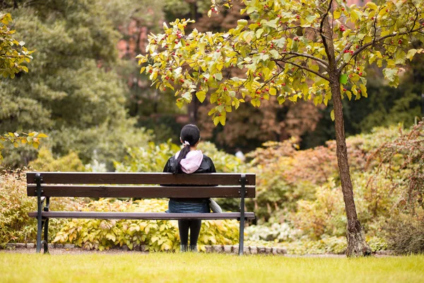 Menina sentada em um banco em um parque — Fotografia de Stock