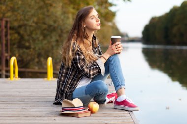 Bir iskelede oturan genç güzel kız