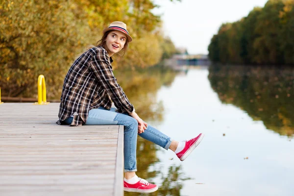 Giovane bella ragazza seduta su un molo — Foto Stock