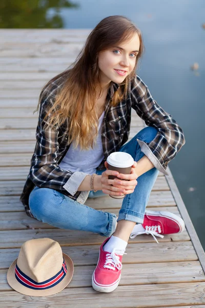 Junges schönes Mädchen sitzt auf einem Pier — Stockfoto