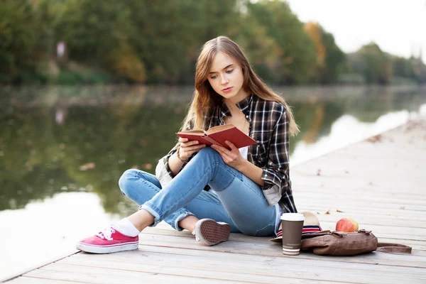 Junges schönes Mädchen sitzt auf einem Pier — Stockfoto