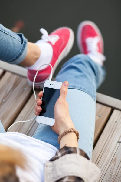 WROCLAW, POLÓNIA - 12 de outubro de 2014: Adolescente sentado em um cais segurando um smartphone Apple iPhone — Fotografia de Stock