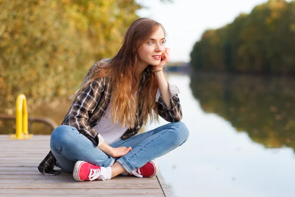 Молодая красивая девушка сидит на пирсе — стоковое фото