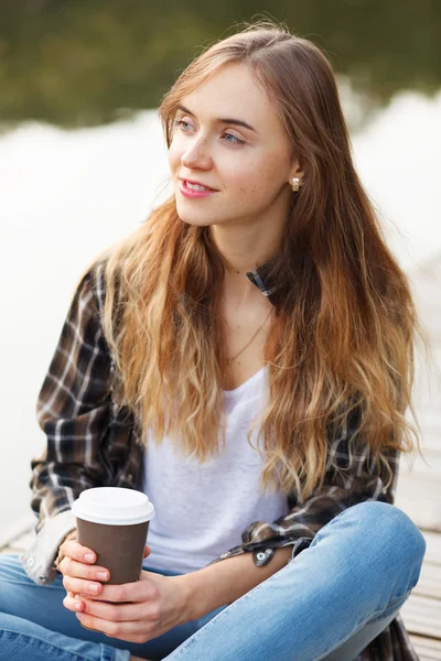 Jovem menina bonita sentada em um cais — Fotografia de Stock