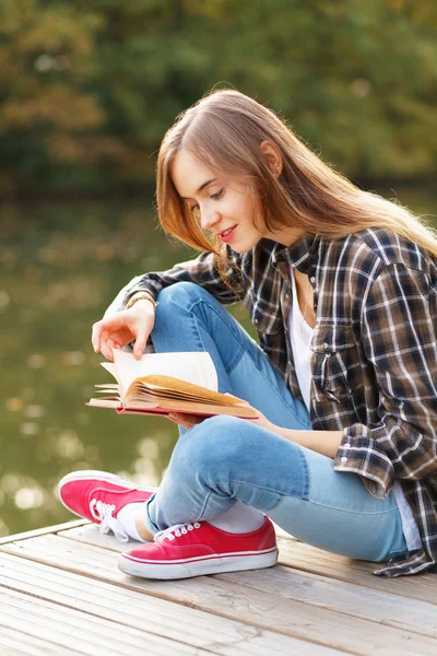 Junges schönes Mädchen sitzt auf einem Pier — Stockfoto