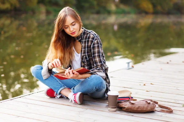 Young beautiful girl sitting on a pier — Stock Photo, Image