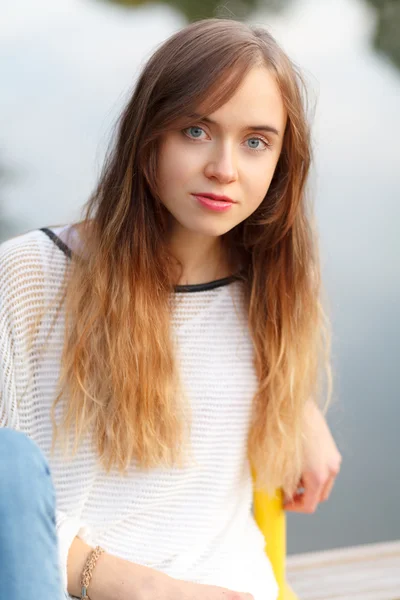 Jovem menina bonita sentada em um cais — Fotografia de Stock