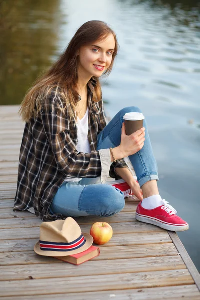 Jovem menina bonita sentada em um cais — Fotografia de Stock