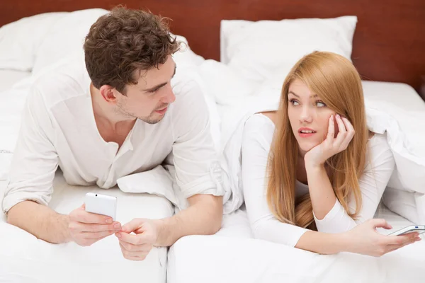 Jong koppel in bed met een smartphone — Stockfoto