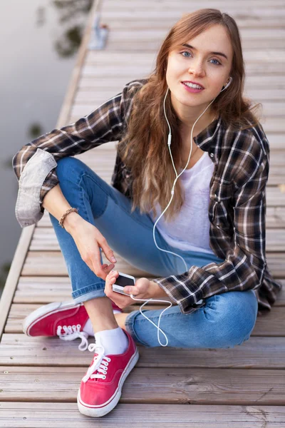 Jovem menina bonita sentada em um cais — Fotografia de Stock