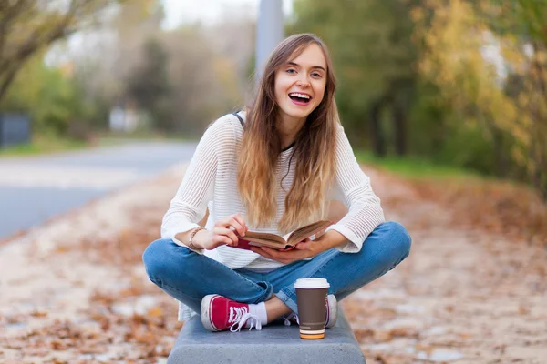 Young beautiful girl sitting on a bench in a park — Stock Photo, Image