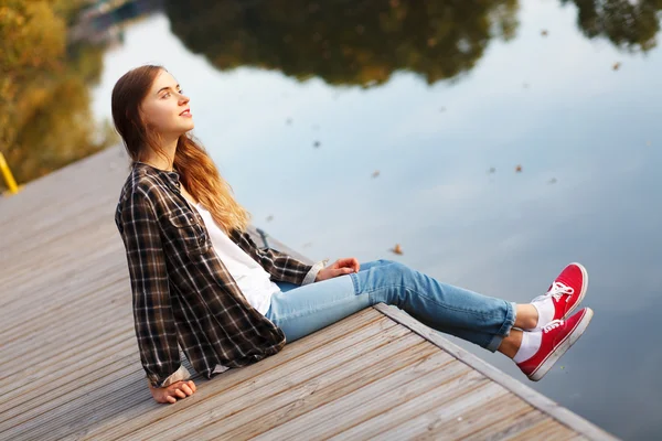 Mooi meisje, zittend op een pier — Stockfoto