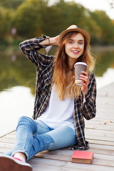 Jovem menina bonita sentada em um cais — Fotografia de Stock