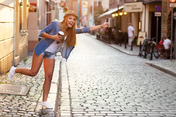 Jonge stijlvolle vrouw drinken koffie te gaan in een stad straat — Stockfoto