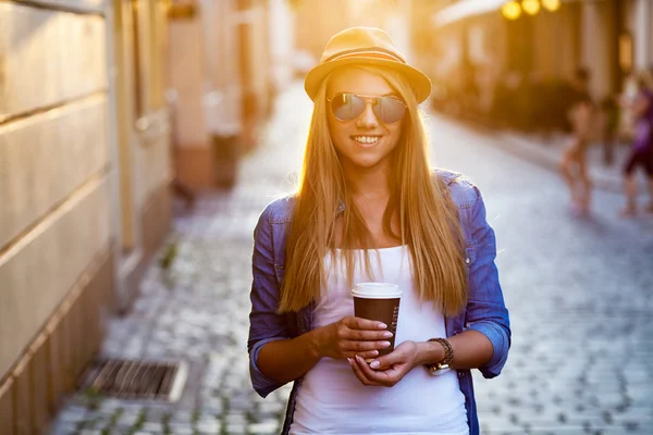 Jonge stijlvolle vrouw drinken koffie te gaan in een stad straat — Stockfoto