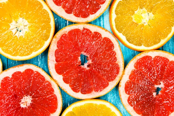Красные грейпфрутовые ломтики на синем деревянном фоне — стоковое фото