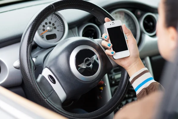 WROCLAW, POLÓNIA - 05 de agosto de 2014: Foto de uma jovem mulher sentada em um carro Mini Cooper segurando um dispositivo smartphone iPhone 4 — Fotografia de Stock