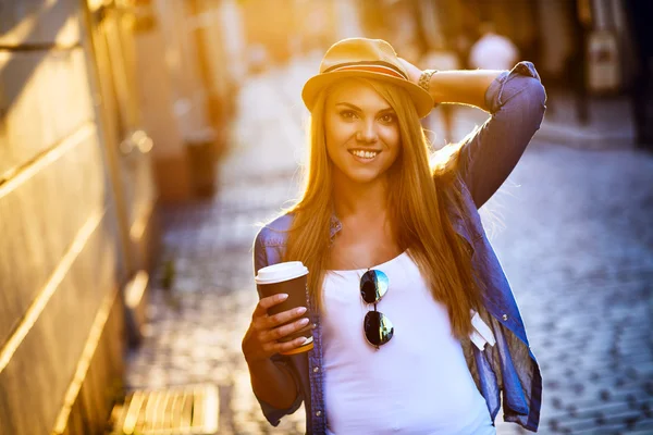 Ung snygg kvinna dricker kaffe för att gå på en stadsgata — Stockfoto