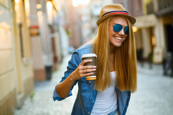 Молодая стильная женщина пьет кофе на городской улице — стоковое фото
