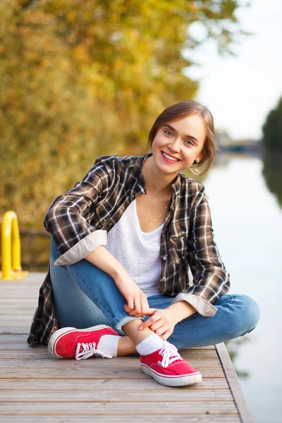 Молода красива дівчина сидить на пірсі — стокове фото