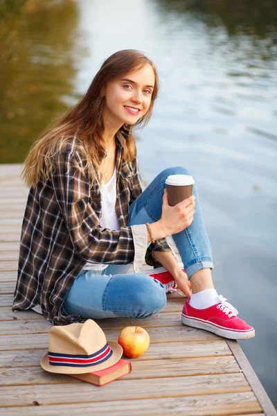 Giovane bella ragazza seduta su un molo — Foto Stock