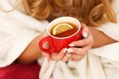 Bir fincan limonlu çay tutan kadın.