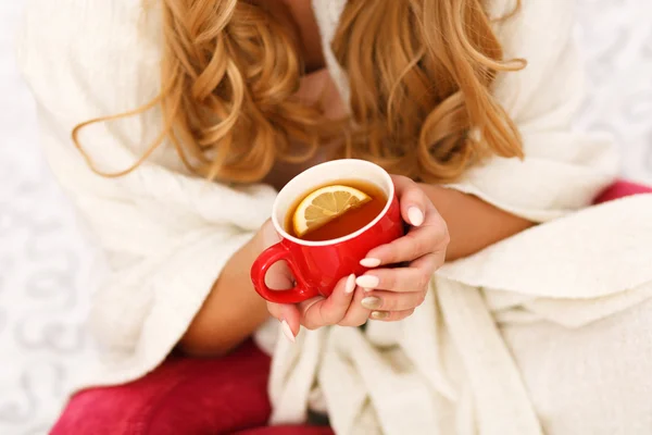 Frau hält eine Tasse Tee mit Zitrone — Stockfoto