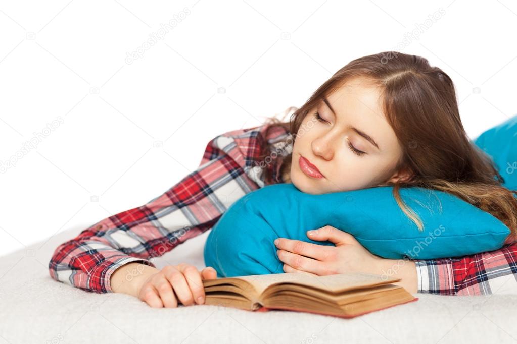 Young girl slepping with a book in bed